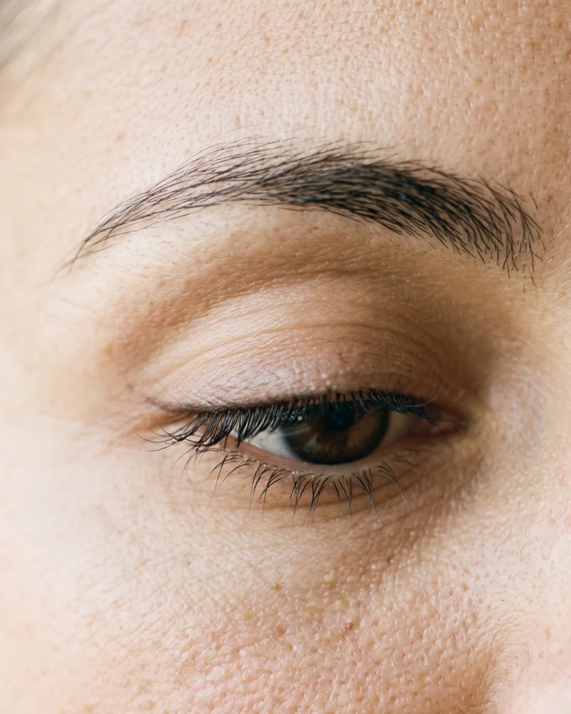 Oog met een fijne permanente eyeliner tussen de wimpers, discreet en natuurlijk.